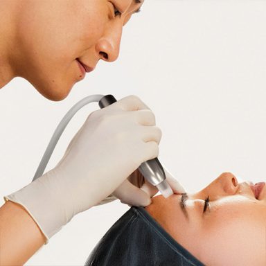Dermatologe führt eine Hautbehandlung bei einer Frau durch.